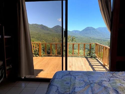 Un dormitorio con una puerta abierta a una terraza con montañas. en Entre Montañas, en Juayúa