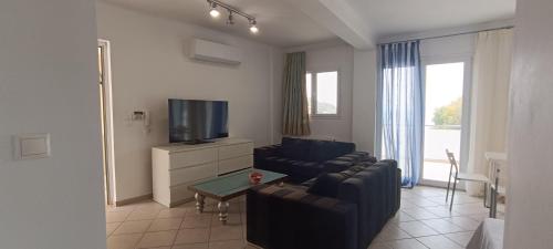 ein Wohnzimmer mit einem Sofa und einem TV in der Unterkunft New Aegli Resort Hotel in Poros