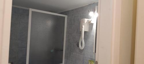 uma casa de banho com um chuveiro e um telefone na parede em New Aegli Resort Hotel em Poros
