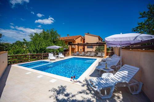 una piscina con sedie e ombrelloni su un patio di E-M Apartments with Private pool a Medulin