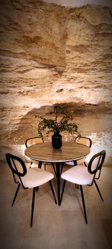 a table with two chairs and a vase with a plant at Casa Cueva Las Chicas del Puente in Setenil