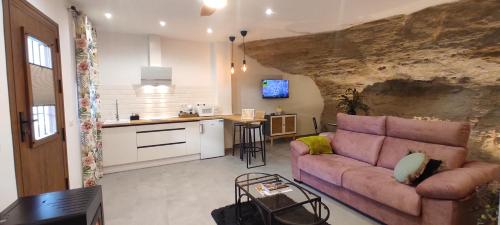 a living room with a couch and a kitchen at Casa Cueva Las Chicas del Puente in Setenil