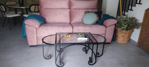 a living room with a pink couch and a glass table at Casa Cueva Las Chicas del Puente in Setenil