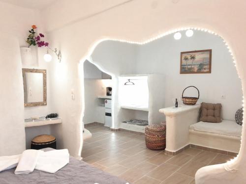 ein weißes Zimmer mit einem Bett und einem Tisch in der Unterkunft Lavish Sunset Suite Arkasa in Arkasa