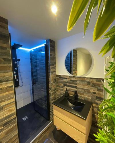 La salle de bains est pourvue d'un lavabo noir et d'une douche. dans l'établissement Love room: Aux plaisirs des sens jacuzzi privé, à Barr