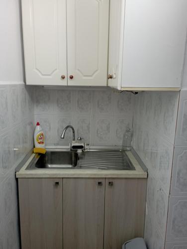 a small kitchen with a sink and white cabinets at Lola's Apartament in Berat