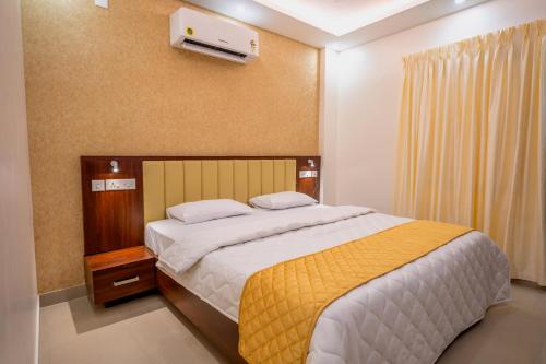 a bedroom with a large bed with a yellow blanket at Metro Residency in Tirūr