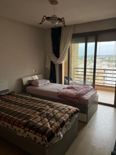 une chambre avec deux lits et une grande fenêtre dans l'établissement Plage des nations, à Sale