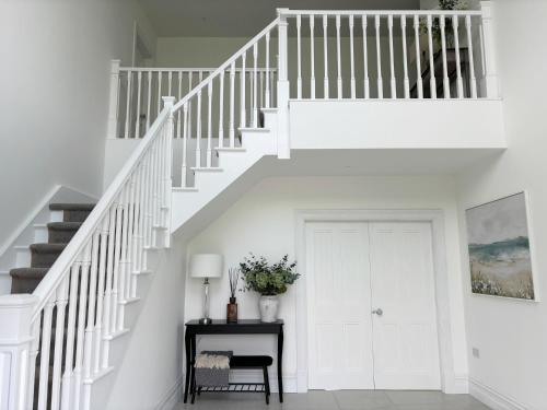 eine weiße Treppe in einem Haus mit einem Tisch in der Unterkunft Eastbury House P25 C3K8 in Cork