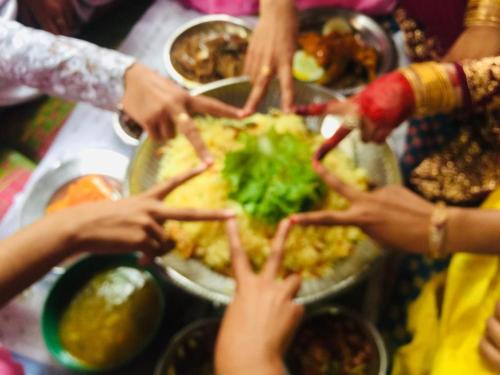 a group of people putting their hands together on a table with food at Nilaveli Guest House in Nilaveli