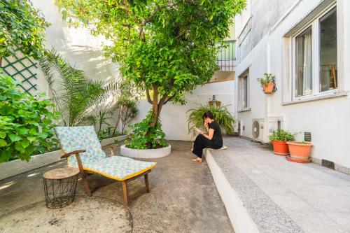 a woman sitting on the side of a building next to a tree at Pátio da Laranjeira in Tomar