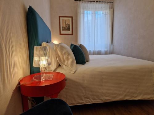 a bedroom with a bed and a red table with a lamp at Lo Strullo in Pisa