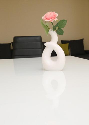 a white vase with a pink rose in it on a table at Haris Studio 2 in Keramotí