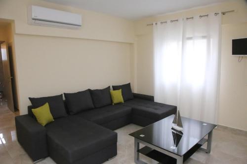 a living room with a black couch and a table at Haris Studio 2 in Keramotí
