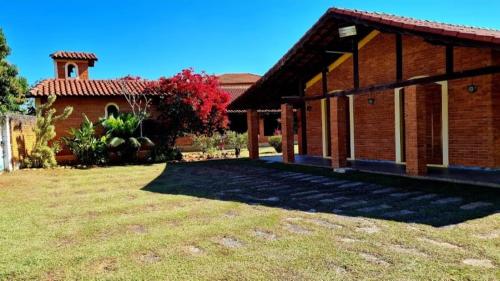 a house with a grass yard next to a building at Chácara em Boituva com piscina e churrasqueira in Boituva
