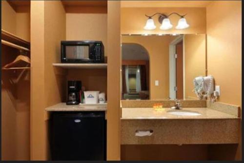 baño con lavabo, espejo y microondas en Days Inn by Wyndham Lubbock South, en Lubbock