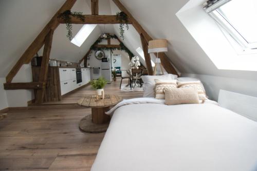 um quarto com uma cama branca num sótão em LE RELAIS DES CALECHES - l'Appartement "L'aparté" 