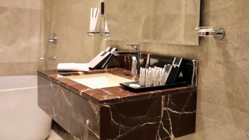 Five Seasons Hotel في تبوك: حمام مع حوض ومرآة