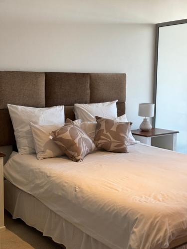 a large white bed with pillows on it at Cosy one bedroom apartment in Windhoek