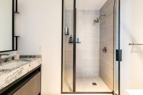 y baño con ducha y puerta de cristal. en 1+Den/1 Luxury apartment in Seaport en Boston