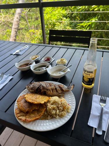 a table with a plate of food and a bottle of beer at Hostel-Island Paradise, Saboga Lodge and Villa Noelia in Panama City