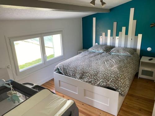 une chambre avec un lit et un mur bleu dans l'établissement Maison au calme, à Saint-Nazaire-sur-Charente