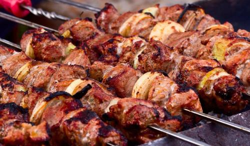 a bunch of food on a grill with tongs at Colibri Home in Kutaisi