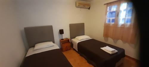 two beds in a small room with a window at Pension Selenti in Tinos Town