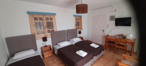 a bedroom with two beds and a desk and a desk at Pension Selenti in Tinos Town