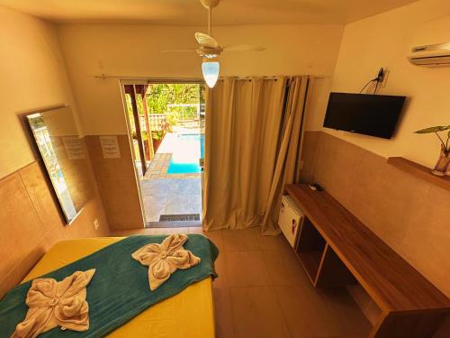 a bedroom with a bed and a television and a pool at Mata Virgem Hostel e Pousada in Abraão