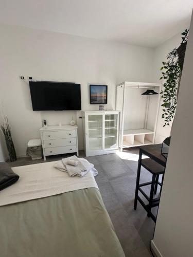 Un dormitorio blanco con una cama y un televisor. en La Quercia, en La Spezia