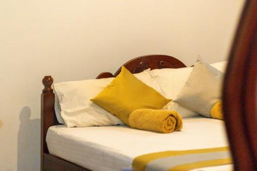 a bed with yellow and white pillows on it at Xotic Resort in Kurunegala