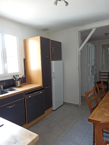 - une cuisine avec des armoires noires et un réfrigérateur blanc dans l'établissement La Chênaie, à Linars