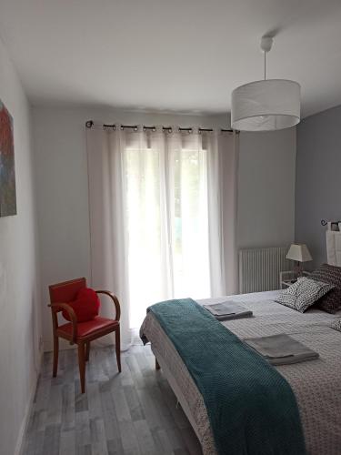 a bedroom with a bed and a chair and a window at La Chênaie in Linars