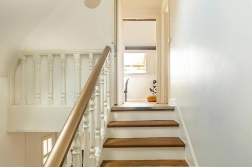 un escalier dans une maison aux murs blancs et au parquet dans l'établissement Chambre confortable JO 2024, à Nogent-sur-Marne