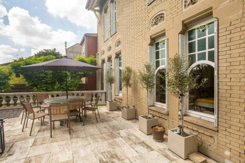 un patio avec une table, des chaises et un parasol dans l'établissement Chambre confortable JO 2024, à Nogent-sur-Marne