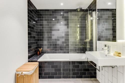 a bathroom with a white tub and a sink at Khayat Homes - The Khalifa - One Bed Luxury APt in London