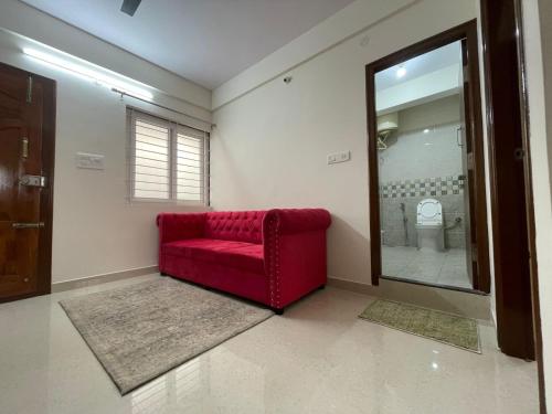 a red couch in a room with a mirror at HSR Lodestone by Newstays in Bengaluru