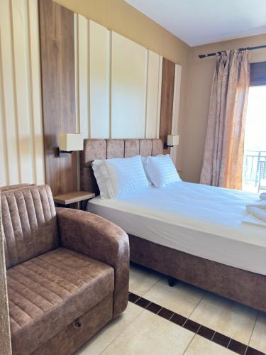 a bedroom with a bed and a chair and a window at Saint George Sithonia in Neos Marmaras