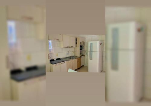a kitchen with white cabinets and a refrigerator at Casa aconchego em Blumenau in Blumenau