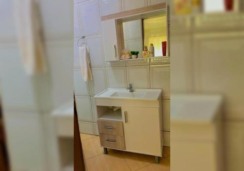 a small bathroom with a sink and a mirror at Casa aconchego em Blumenau in Blumenau
