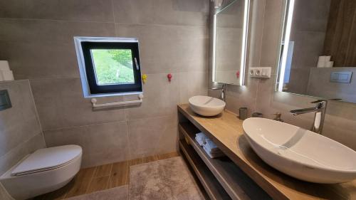 a bathroom with two sinks and a toilet and a window at Chalets Hrabovo in Ružomberok