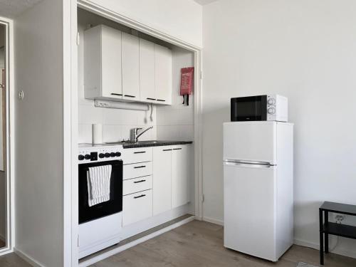 a white kitchen with a refrigerator and a microwave at Travel Center Studio in Pori