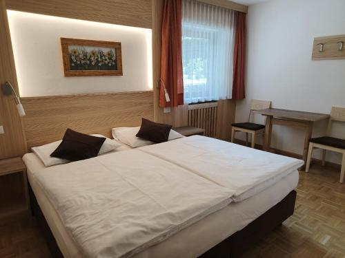 ein Schlafzimmer mit einem großen weißen Bett in einem Zimmer in der Unterkunft Apartments Elise in Wolkenstein in Gröden