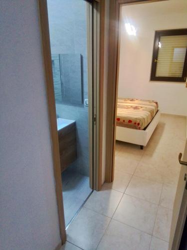1 dormitorio con 1 cama y puerta de cristal que conduce a un baño en Casa Materdomini, en Brindisi