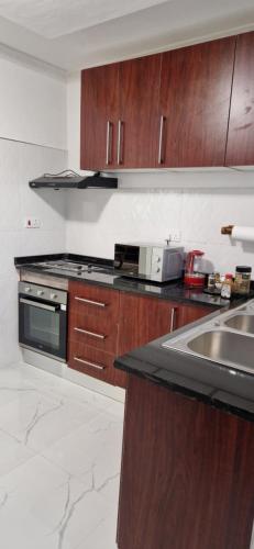 een keuken met houten kasten en een fornuis met oven bij Shalom Apartments Kalumbila in Musele