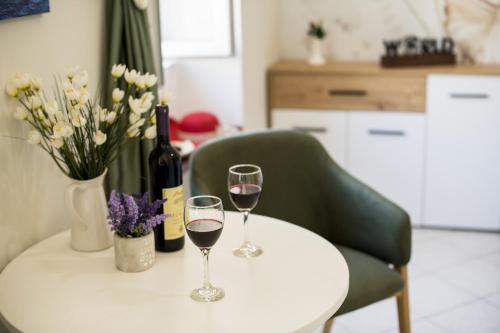 two glasses of wine on a white table with flowers at Apartmani Zukic in Risan