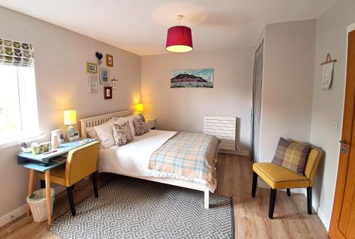 a bedroom with a bed and a desk and a table and chairs at An Cois Na Mara Bed & Breakfast in Laide