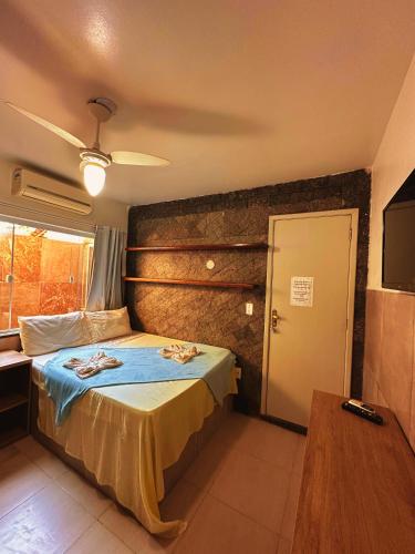 a bedroom with a bed with blue sheets and a television at Mata Virgem Hostel e Pousada in Abraão