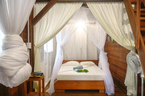 1 dormitorio con cama con dosel y cortinas blancas en La tarima del colibri Ecolodge, en El Valle